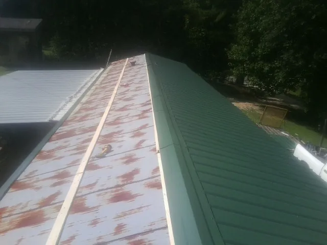 Old rusted panels beside newly installed green metal roofing — Wind Damage Roof Repair by Roofing Brothers in Belgrade