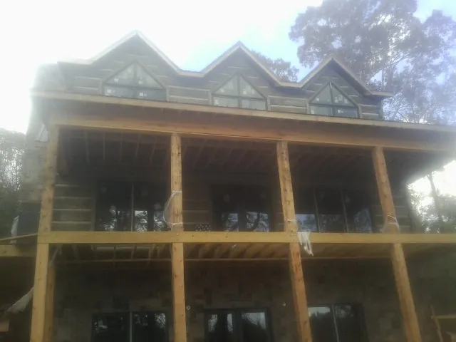 Dormers and porch framing on a large log home under construction — Roof Coating work by our crew in Belgrade