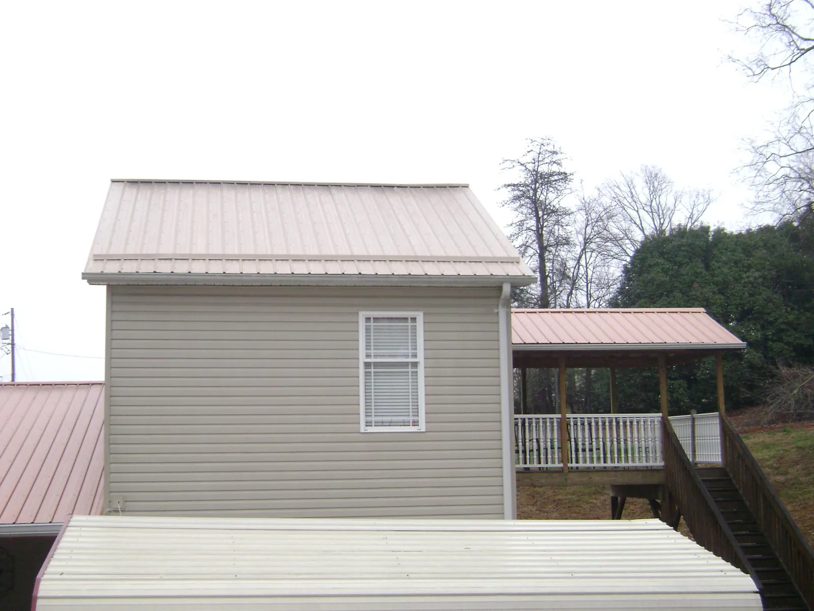 Tan metal roofs on a two story addition and attached porch in Belgrade